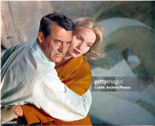 Cary Grant holding Eva Marie Saint in a scene from the film 'North By Northwest', 1959. Grant is wearing a pale grey Oxford shirt by Brooks Brothers.