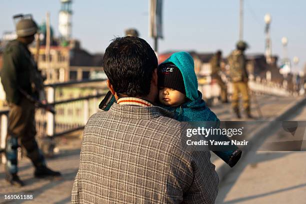 Kashmiri man holds his baby during a curfew after Mohammad Afzal Guru was executed for plotting to attack India's parliament on February 09, 2012 in...