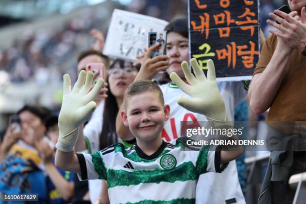 Young football fan wearing a Celtic FC shirt poses with gloves given by Tottenham Hotspur's English goalkeeper Fraser Forster who was a former Celtic...