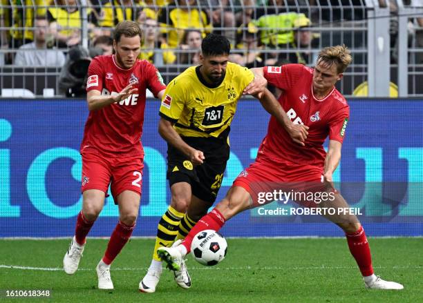 Dortmund's German midfielder Emre Can and Cologne's German defender Benno Schmitz and Cologne's German defender Timo Huebers vie for the ball during...