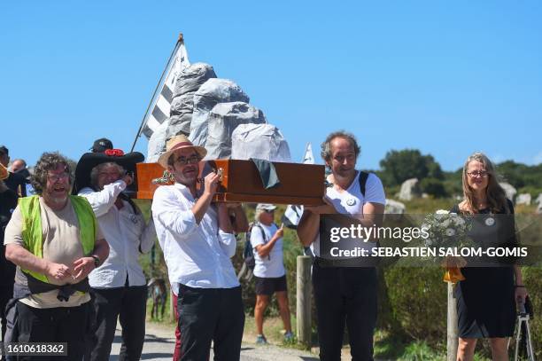 Protesters hold Brittany flags and a coffin containing false standing stones as they take part in a march called by the Stones Uprising , a new...