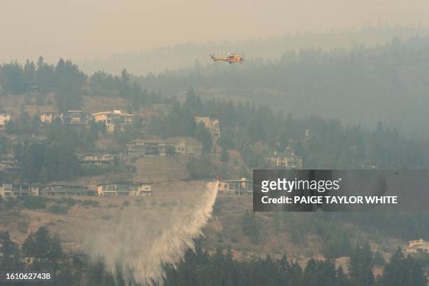 Helicopter drops water as the McDougall Creek wildfire continues to burn in West Kelowna, British Columbia, on August 19, 2023. Around 30,000 people...