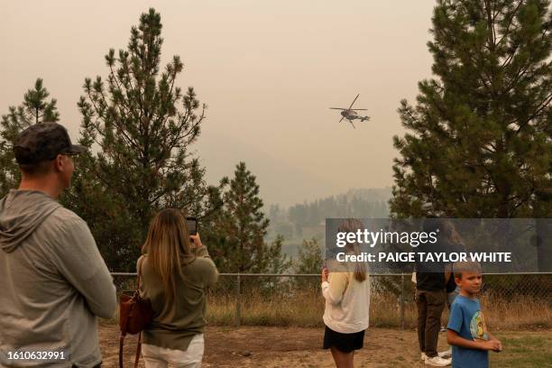 David and Natalie Walden and their neighbour Stefania Wiik, her son Kenneth and a couple watch as a helicopter gathers water at Shannon Lake to...