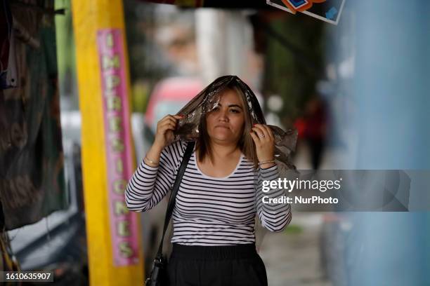 Woman covers her head with plastic while it rains in Mexico City. This Saturday, heavy rains were registered in Mexico City due to Tropical Cyclone...