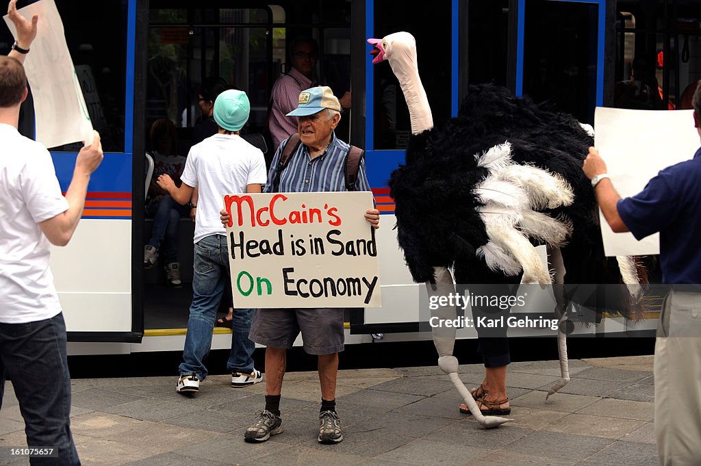 (KG) OSTRICH -- Manny Salzman, holding sign, and his daughter Naomi, in the ostrich costume, protested with a handful of others affilliated with the group Progress Now Action. They said Republican presidential candidate John McCain has his head in the san