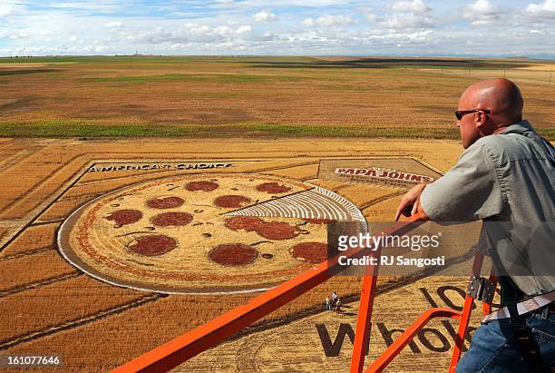 Marc Wilson, who runs the 86 foot boom truck, look out over a wheat field a mile off the east-west DIA runways that Papa John&amp;trade;s has crafted...