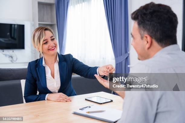 the real estate agent giving a house key after successfully selling a new house - lease agreement stock pictures, royalty-free photos & images