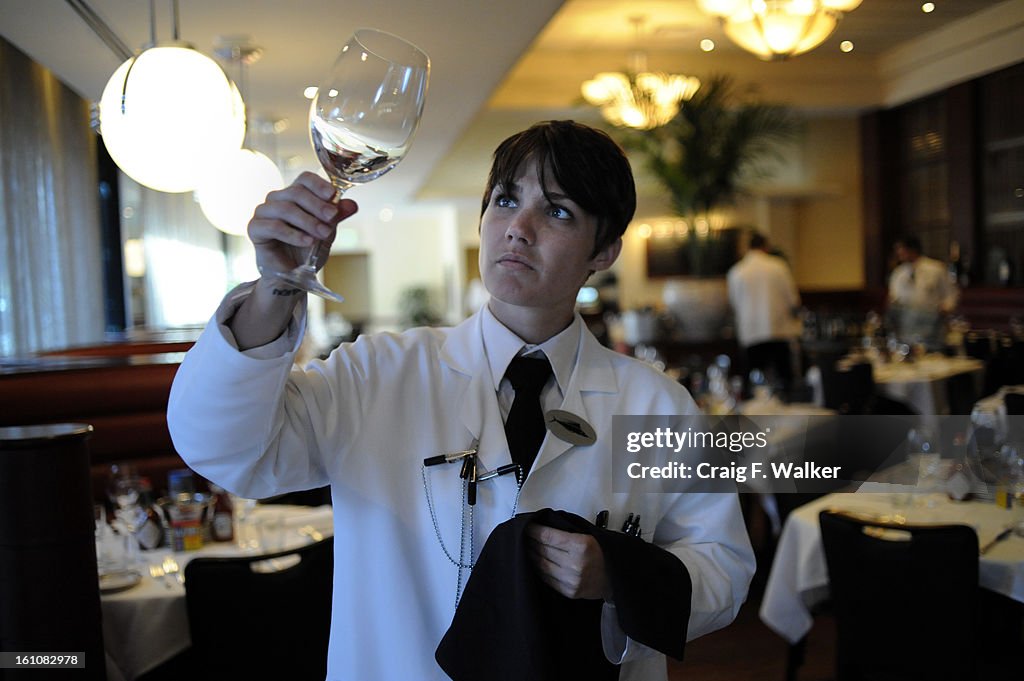 (XX)DNCBRESTAURANTS_082108_CFW -Server Morgan McDonald polishes glasses and silverware before opening for dinner at the Oceanaire Seafood Room in downtown Denver, CO. During a pre-shift meeting General manager Bob Bonner advised his staff to rely on publi