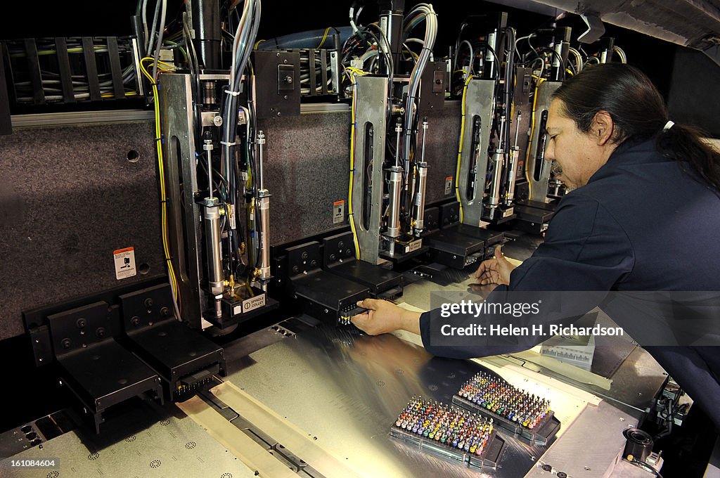 (EL) ABOVE: Jerry Lopez changes out the drill bits on the Excellon 689 drill machine. The large machine uses 6 spindles, with dozens of drill bits on each spindle, to drill the most precise holes in the circuit boards. The machine is electronically progra
