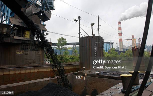 As coal is poured into a waiting barge, smoke billows from a coal powered electric plant August 26, 2001 in western, PA. The coal mining industry,...