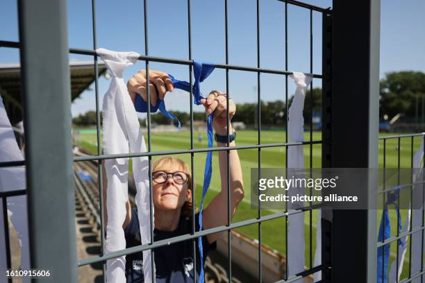 August 2023, Berlin: Regionalliga women: Hertha BSC - Union Berlin. Inis hangs blue and white ribbons on a fence before the women's regional league...