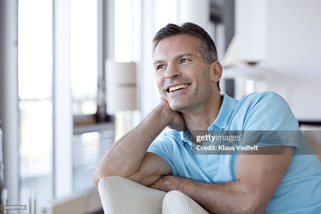 Portrait of man laughing in livingroom chair