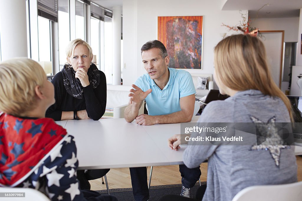 Family of 4 having a discussion at dinner table