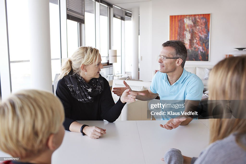 Family of 4 having a discussion at dinner table