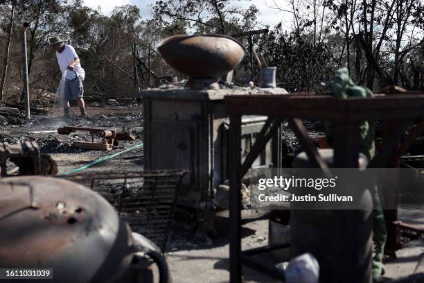 Resident uses a garden hose to put out hot spots after his home was destroyed by wildfire on August 12, 2023 in Kula, Hawaii. At least 80 people were...