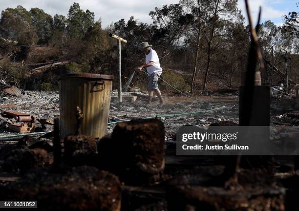 Resident uses a garden hose to put out hot spots after his home was destroyed by wildfire on August 12, 2023 in Kula, Hawaii. At least 80 people were...