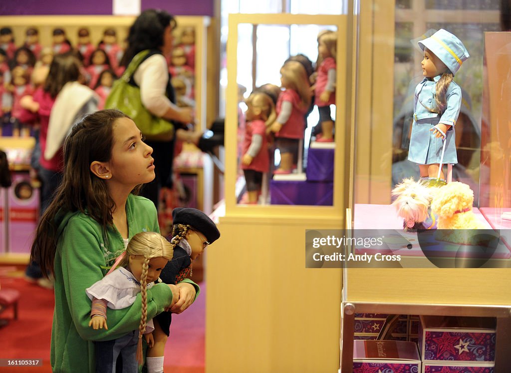 HIGHLANDS RANCH,CO--MARCH 26TH 2010--Jazmyn Andre, 10-yesars-old from Parker, looks at an American Girl doll in a glass case, holding two American Girl dolls, one that she already had and another that she just bought at the new American Girl doll store in