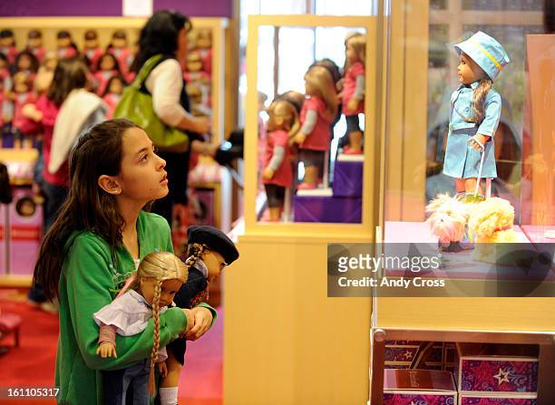 Jazmyn Andre, 10-yesars-old from Parker, looks at an American Girl doll in a glass case, holding two American Girl dolls, one that she already had...