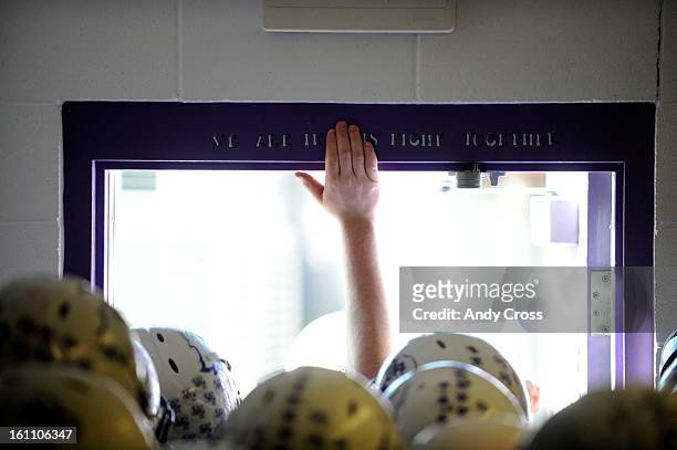 Wray Eagles football player taps his hand on a sign above the locker room door that states, "We are in this fight together" taking the field against...