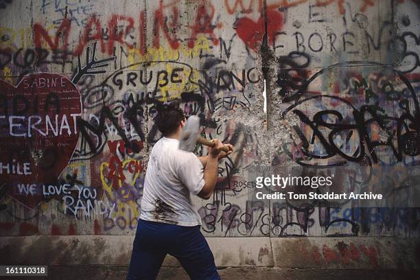 Man hammers at the wall in Berlin, during the Fall of the Berlin Wall, 10th November 1989.