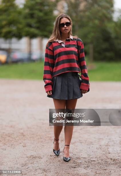 Guest seen wearing black sunnies, black and white striped Ralph Lauren shirt, grey folded mini skirt and black shiny sandals outside Opera Sport show...