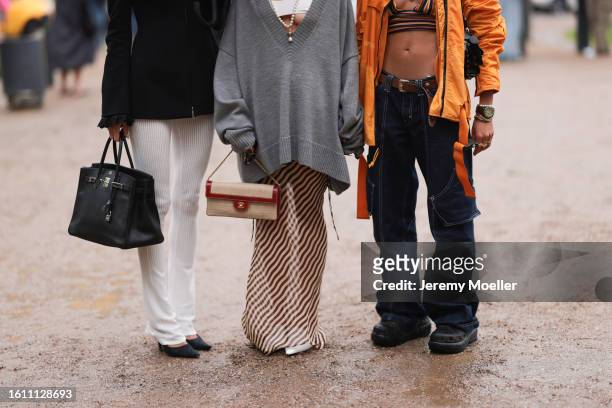 Selma Kaci is seen wearing lilac sunnies, Paco Rabanne golden earrings and necklaces, colorful striped bra top, oversized orange outwear jacket, low...