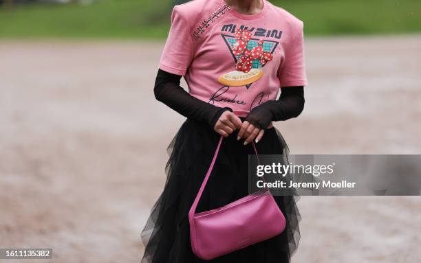 Guest seen wearing black sunnies, big silver hoop earrings, pink cropped asymmetric top with silver details and colorful prints, black long sleeve...