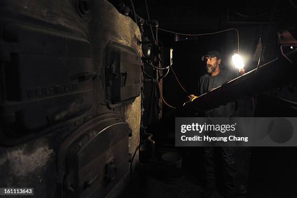 John Schertz of John's Outback Coal Boiler Service checks the broken coal boiler at the basement of school gym. Silverton's K-12 school has been...