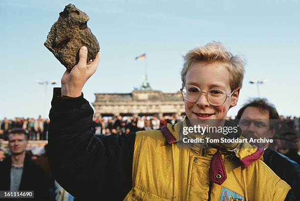 Bystander holds a souvenir chunk of masonry from the Berlin Wall, during the Fall of the Berlin Wall, 10th November 1989.