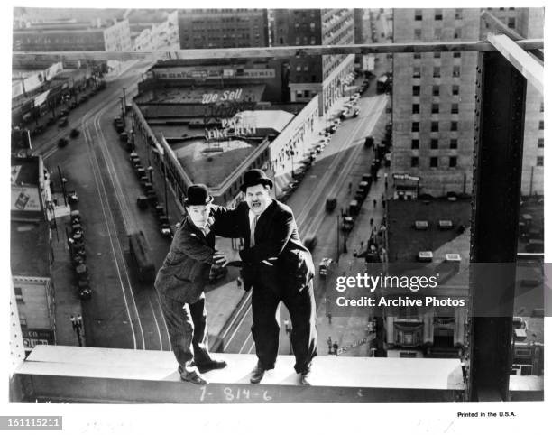 Stan Laurel and Oliver Hardy stand on the edge of a building in a scene from the film 'Liberty', 1929.
