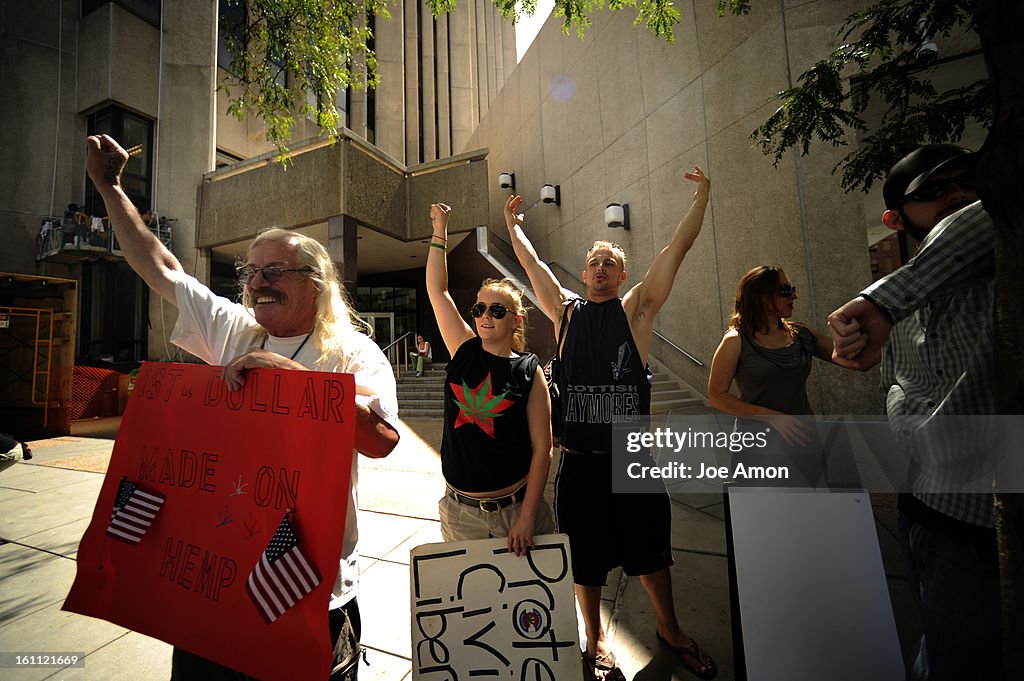 Medical marijuana activist's "Wayward" Bill Chengelis, Lauren Laire and passerby Jason Linam react to supporting beeps from cars in front of Wells Fargo as they march in downtown Denver to protest banks in the area closing the accounts with local medical