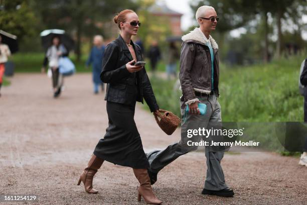 Guest is seen wearing black sunnies, gold chain necklace, black leather blazer, black checkered midi skirt and brown high knee leather boots, Guest...