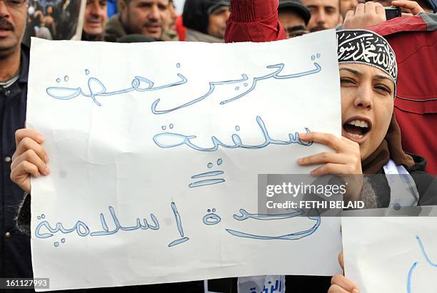 Tunisian woman holds up a sign written in Arabic that reads, "Liberation, Ennahda, Salafist = Islamic Unity " as Ennahda party supporters take part...