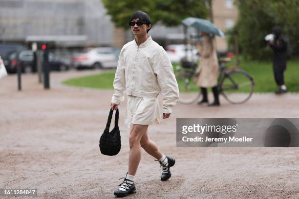 Guest is seen wearing black sunnies, white denim set, black COS handbag and black lace sandals with white socks outside Opera Sport show during the...