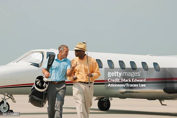 golfers walking on airport tarmac - millionnaire stock pictures, royalty-free photos & images