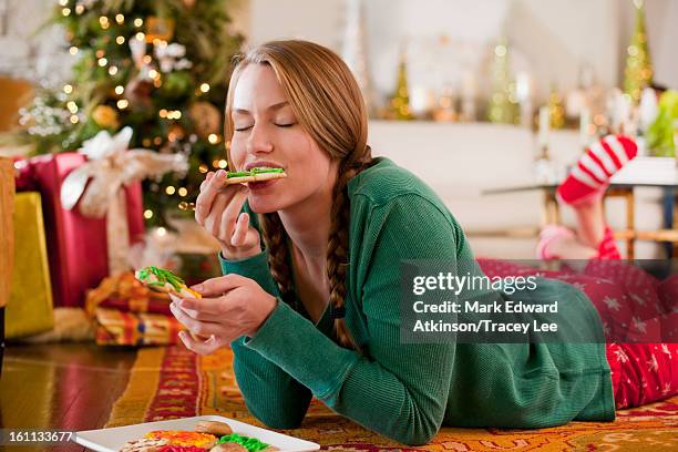 caucasian woman eating christmas cookies - prono foto e immagini stock