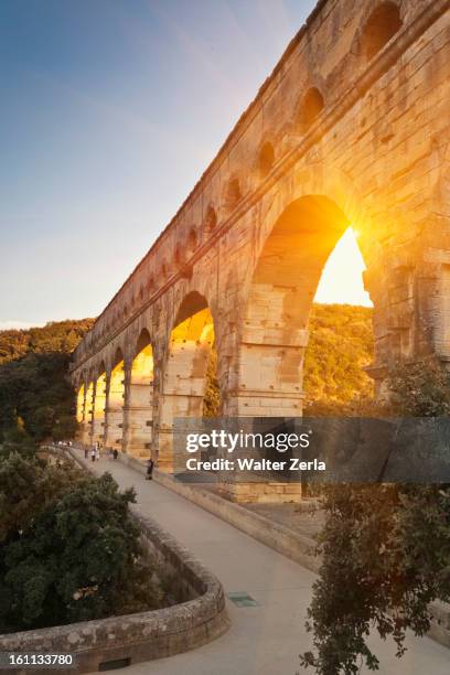 sun shining through aqueduct - pont du gard aqueduct stock pictures, royalty-free photos & images