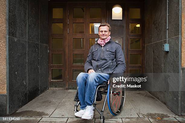 man sitting in wheelchair looking at camera - wheelchair photos et images de collection