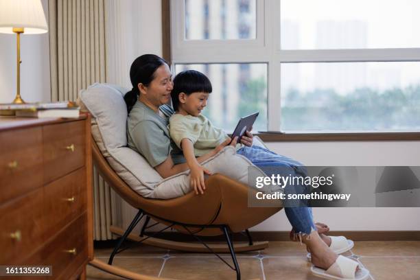 mother and child learn using digital tablets in the living room - china games day 4 stockfoto's en -beelden