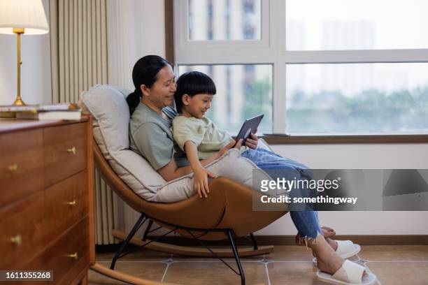 mother and child learn using digital tablets in the living room - china games day 2 stock pictures, royalty-free photos & images