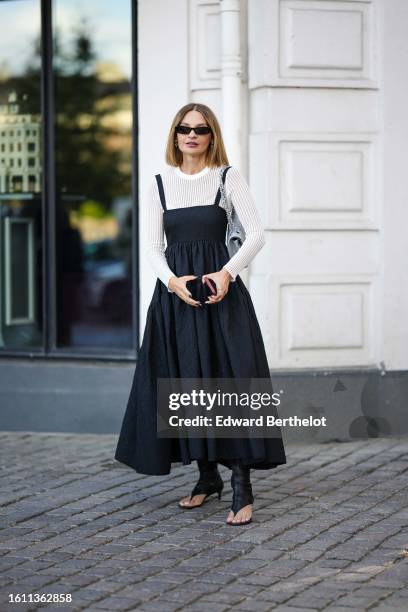 Guest wears black sunglasses, a white striped embossed pattern long sleeves t-shirt, a black squared neck / tank-top long dress, a silver gray shiny...