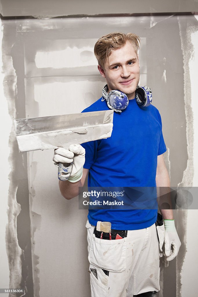 Portrait of happy craftsmen holding caulking blade