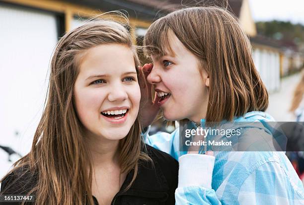 girl whispering in her friend's ear - child whispering stock-fotos und bilder