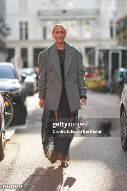 Guest wears gold pearls pendant earrings, a black and white micro checkered print pattern oversized blazer jacket, a black lace print pattern high...