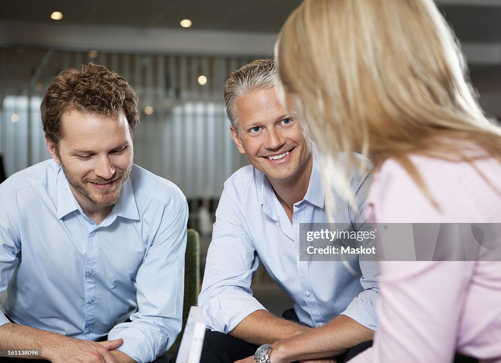 Three business people smiling during a conversation