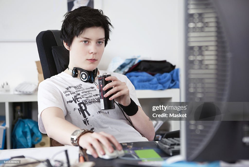 Woman sitting by computer holding a energy drink