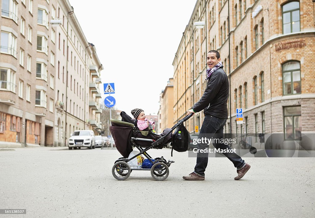 Smiling father walking with cute baby (0-11 months) in stroller