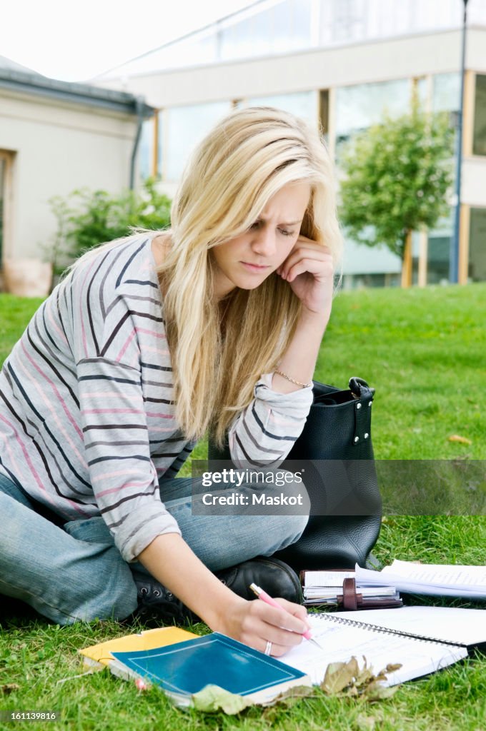 Woman sitting outside writing in notepad