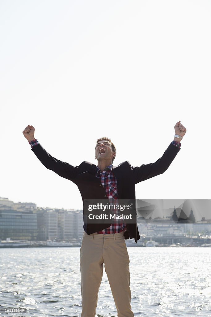 Successful mature businessman screaming with arms outstretched