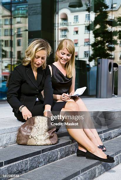 two businesswomen sitting outside making plans - trash bag dress stock pictures, royalty-free photos & images
